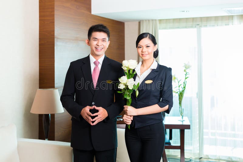 Directeur d'hôtel chinois asiatique souhaitant la bienvenue à des invités de VIP photographie stock Directeur d'hôtel chinois asiatique souhaitant la bienvenue à des invités de VIP photographie stock