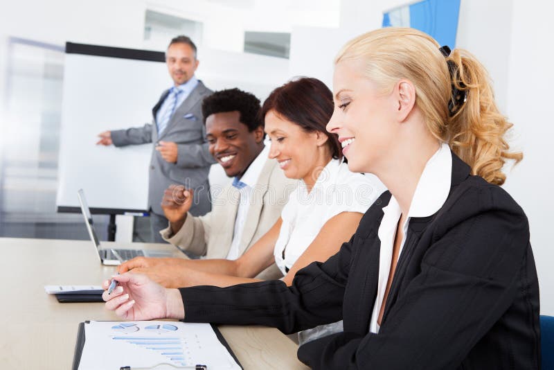 Group of business executives taking notes during a meeting at office. Group of business executives taking notes during a meeting at office