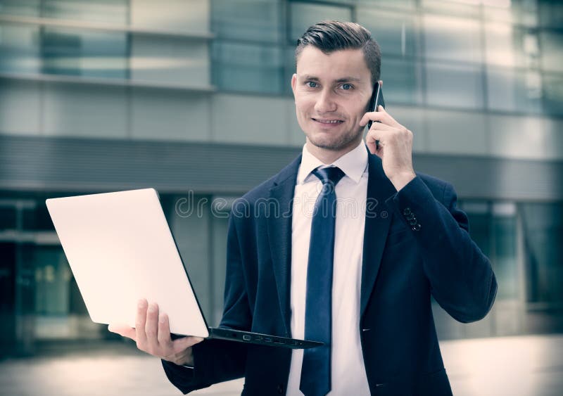 Direttore sta stando con il computer portatile vicino all'ufficio fotografie stock libere da diritti Direttore sta stando con il computer portatile vicino all'ufficio fotografie stock libere da diritti