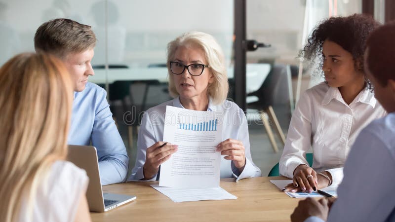 Dirigente aziendale più anziano che presenta risultato finanziario di rapporto alla riunione del gruppo fotografia stock Dirigente aziendale più anziano che presenta risultato finanziario di rapporto alla riunione del gruppo fotografia stock