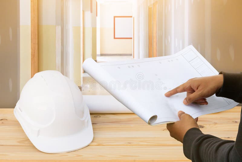 Dirija el punto del finger en el modelo de papel del plan en interior de la pared del tablero de yeso del emplazamiento de la obr fotos de archivo libres de regalías Dirija el punto del finger en el modelo de papel del plan en interior de la pared del tablero de yeso del emplazamiento de la obr fotos de archivo libres de regalías