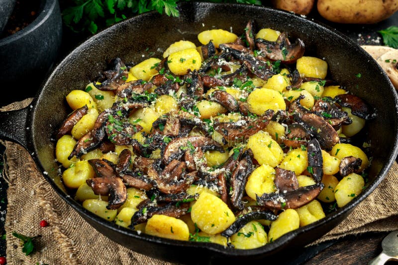 Dirija o gnocchi feito da batata com cogumelos, salsa desbastada e queijo parmesão na bandeja do ferro imagens de stock royalty free Dirija o gnocchi feito da batata com cogumelos, salsa desbastada e queijo parmesão na bandeja do ferro imagens de stock royalty free