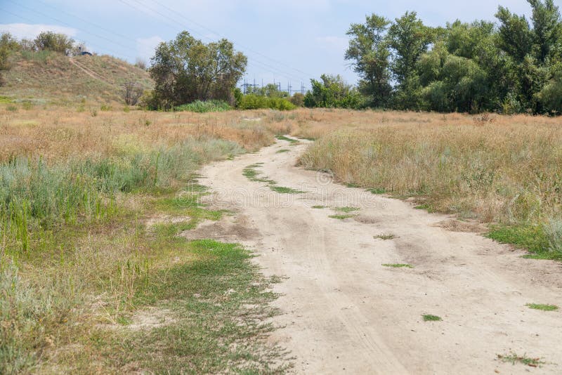 Dirt country road. The dirt country road in clear summer sunny day, with vegetation, a grass and a bush royalty free stock photos Dirt country road. The dirt country road in clear summer sunny day, with vegetation, a grass and a bush royalty free stock photos