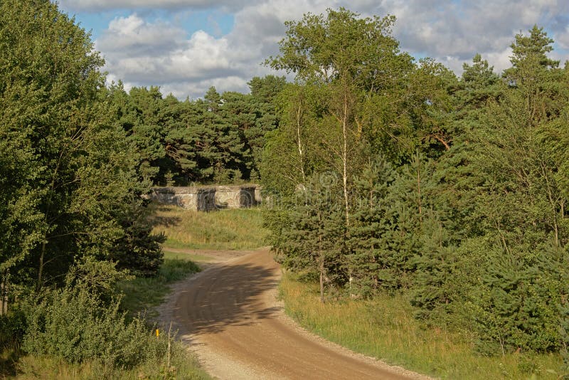Dirt road leading to remains of abandoned sovjet bunkers in the pine forest, part of an old fort in the former Soviet base Karosta in Liepaja, Latvia. Dirt road leading to remains of abandoned sovjet bunkers in the pine forest, part of an old fort in the former Soviet base Karosta in Liepaja, Latvia