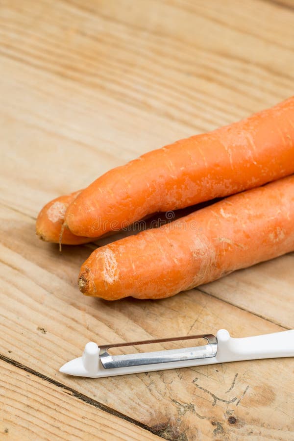 Dirty Carrots with Peeling Knife on the Wooden Table Stock Photo