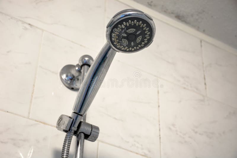 Dirty chrome shower head with limescale that should be cleaned and mold on tiles and ceiling royalty free stock image
