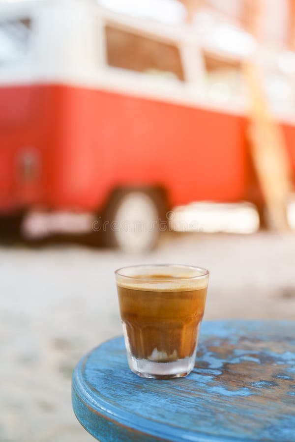 Dirty Coffee : glass of espresso shot mixed with cold fresh milk on blurred beach background