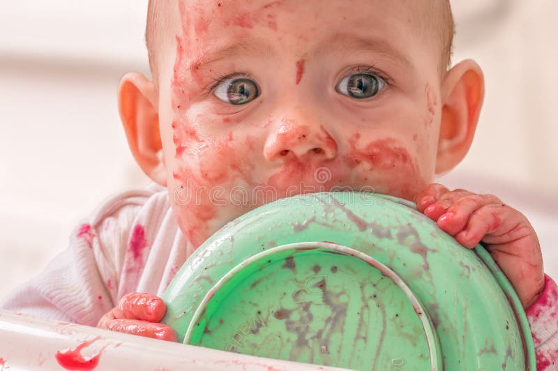 Dirty and messy baby is eating from bowl stock image