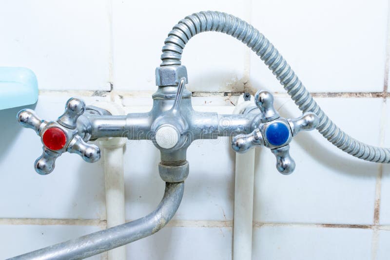 Dirty old faucet with limescale or lime scale on it, dirty calcified and rusty shower mixer tap and hose, moldy tiles on royalty free stock image