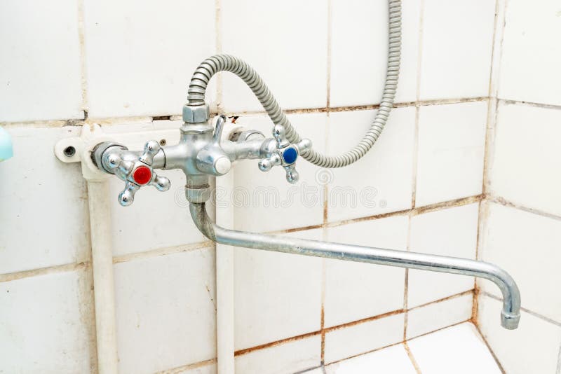 Dirty old faucet with limescale or lime scale on it, dirty calcified and rusty shower mixer tap and hose, moldy tiles on stock photos