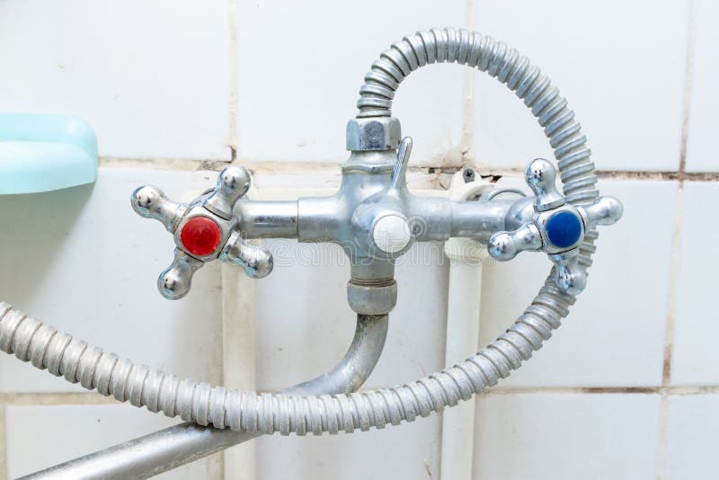 Dirty old faucet with limescale or lime scale on it, dirty calcified and rusty shower mixer tap and hose, moldy tiles on stock photography