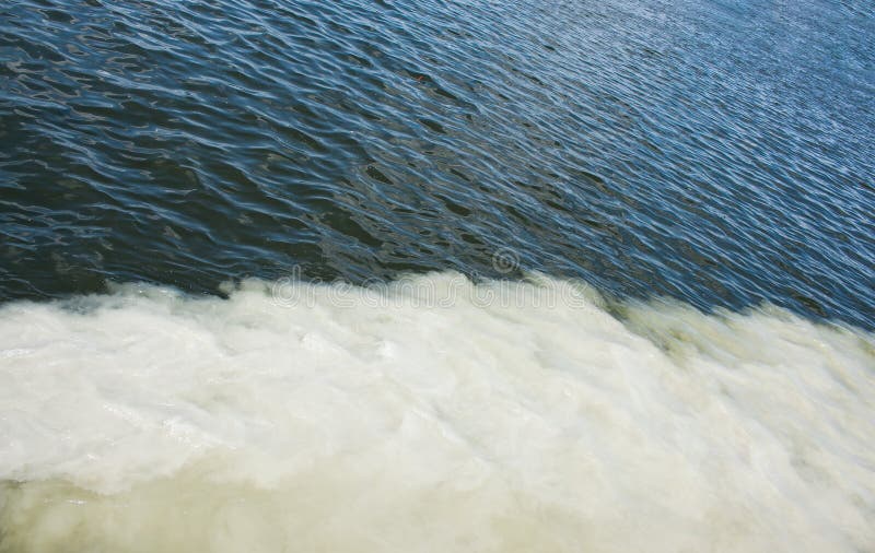 Dirty Orange Water from Sewage Pipeline Mixes with River Water. Stock