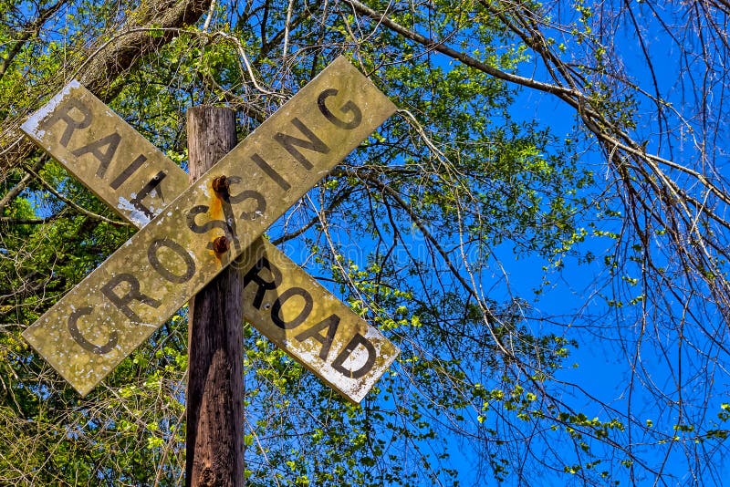 Dirty rail road crossing sign on wooden post