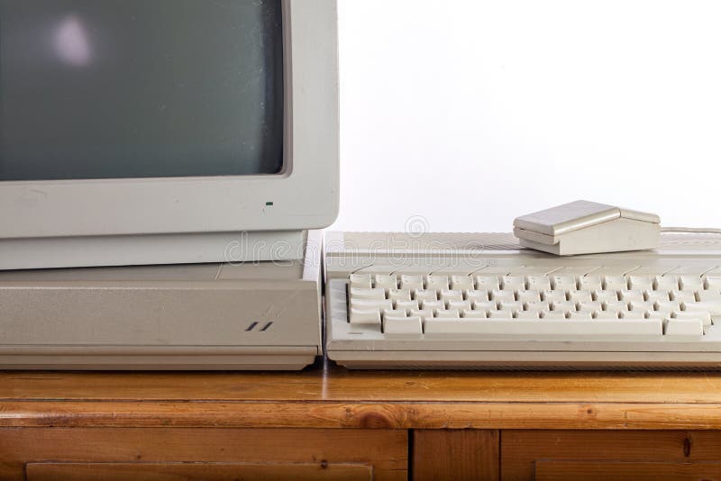 Dirty retro computer system on old pine desk. Outdated computing stock image