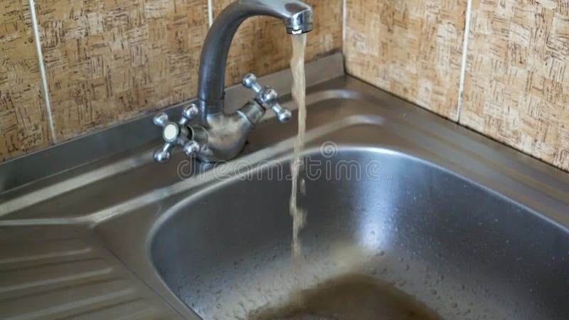 Dirty rusty water flows from the faucet sink stock video