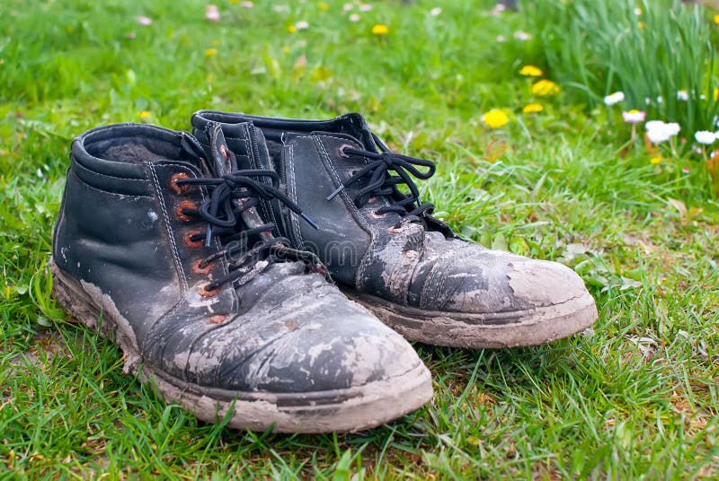Dirty Shoes. Old Worn Out Men`s Boots with Dried Mud on the Green Grass ...