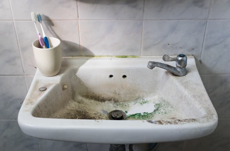 Dirty Sink with Toothbrush and Tap in Dirty Bathroom. Stock Photo