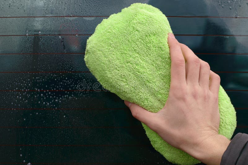 Man washing dirty windshield of car with green sponge. Dirty glass. Purity. Foam. A man washes car glass. Man washing dirty windshield of car with green sponge. Dirty glass. Purity. Foam. A man washes car glass