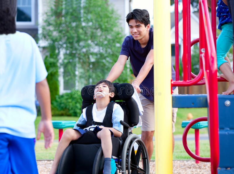 Disabled boy in wheelchair enjoying watching friends play at par