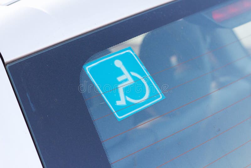 Azul inválido estacionamiento etiqueta sobre el trasero parabrisas de auto.