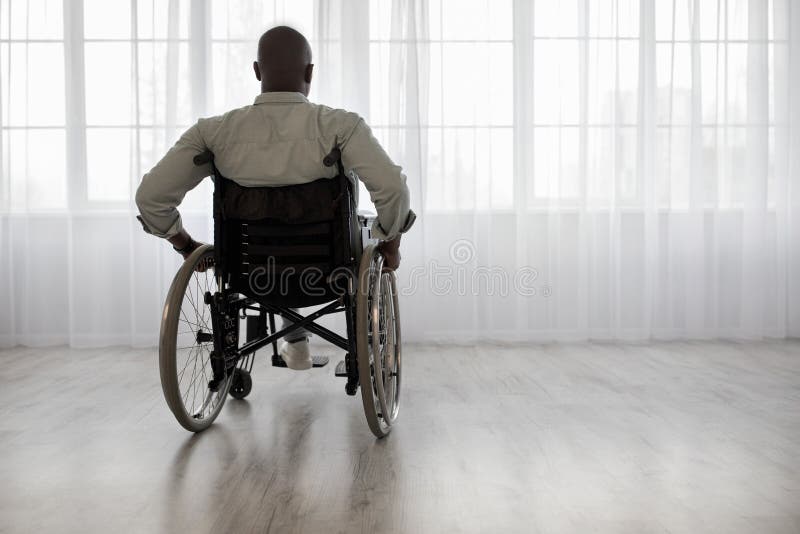 Disabled person sits in wheelchair against window royalty free stock photos