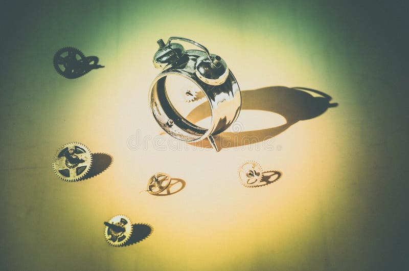 Disassembled alarm clock and scattered gears in bright light with hard shadows stock image Disassembled alarm clock and scattered gears in bright light with hard shadows stock image