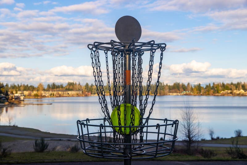 Disc Golf Basket on Pretty Park Course Near a Lake Under Blue Sky Stock