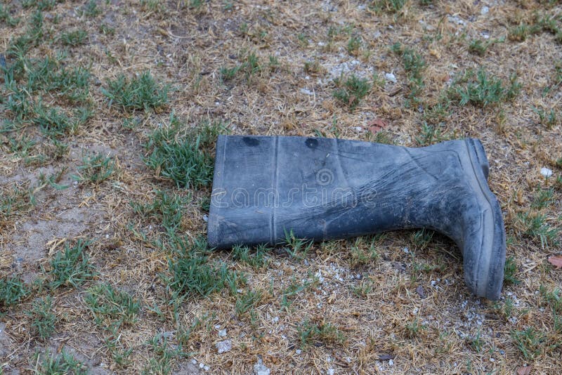 Discarded dirty rubber gumboot on an outdoors background image in landscape format with copy space