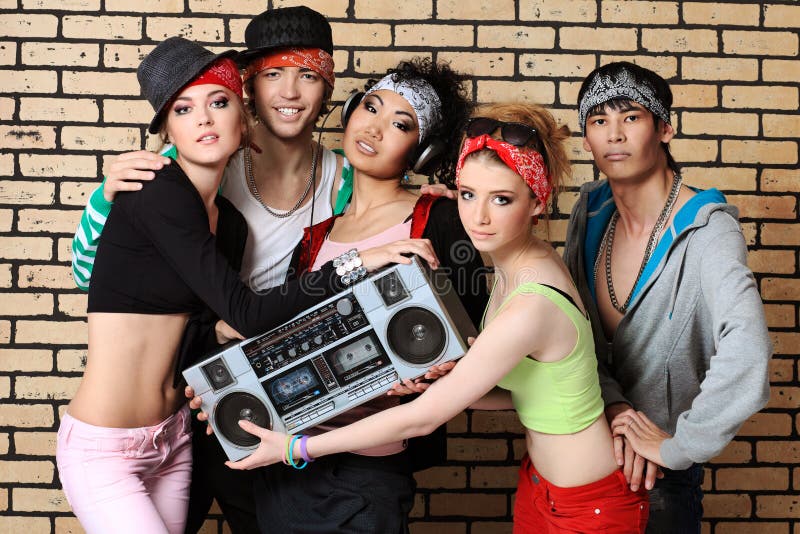 Group of trendy teenagers posing together against a brick wall. Group of trendy teenagers posing together against a brick wall.