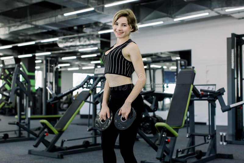 Disco atlético de la tenencia de la mujer joven del barbell y ejercicio en gimnasio imágenes de archivo libres de regalías Disco atlético de la tenencia de la mujer joven del barbell y ejercicio en gimnasio imágenes de archivo libres de regalías