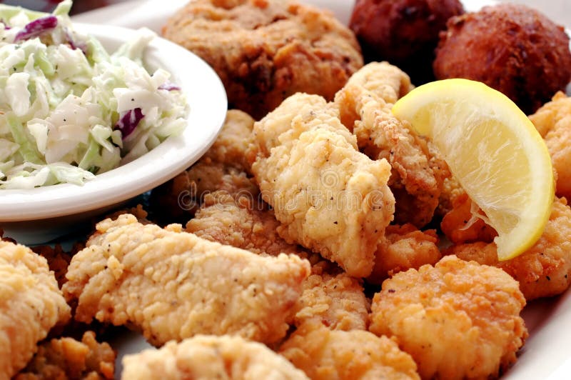 Fried seafood platter with fish, crab cakes, oysters, shrimp, hush puppies, cole slaw, and lemon slice. Fried seafood platter with fish, crab cakes, oysters, shrimp, hush puppies, cole slaw, and lemon slice.