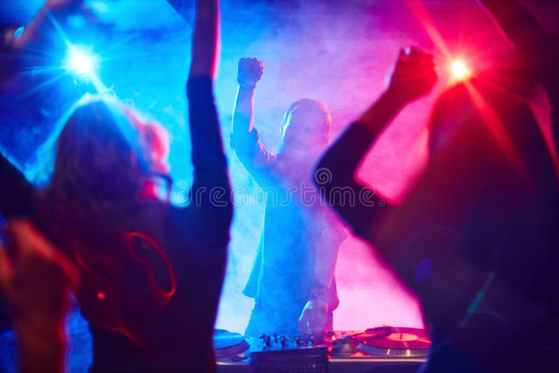 Excited deejay and dancing crowd enjoying disco party in nightclub. Excited deejay and dancing crowd enjoying disco party in nightclub