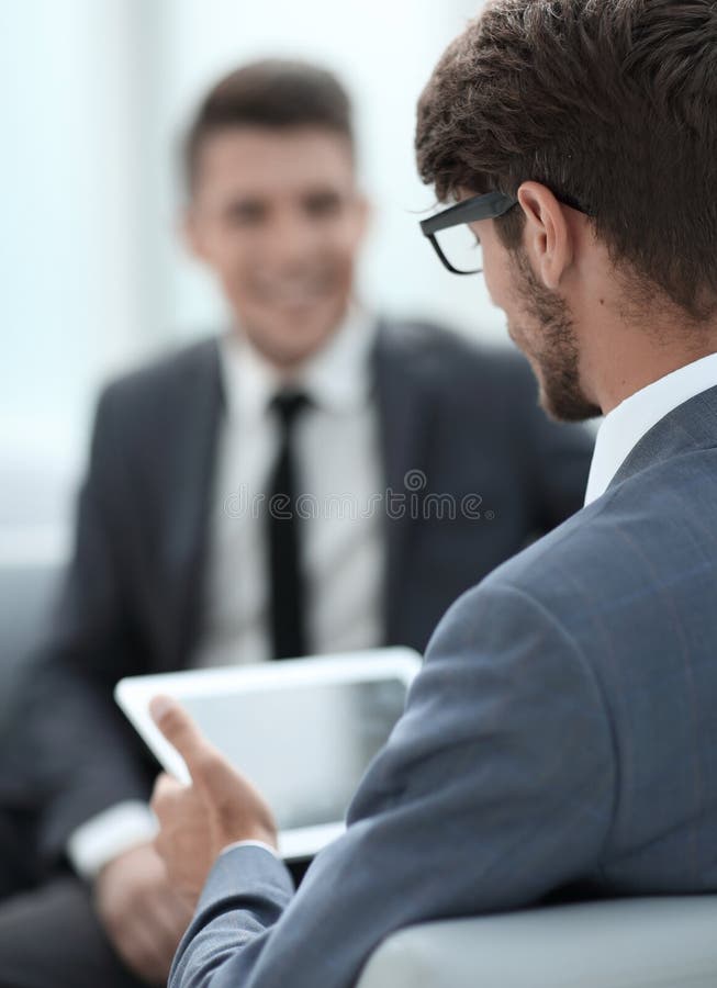 Two young businessmen discuss ideas with a tablet stock images Two young businessmen discuss ideas with a tablet stock images