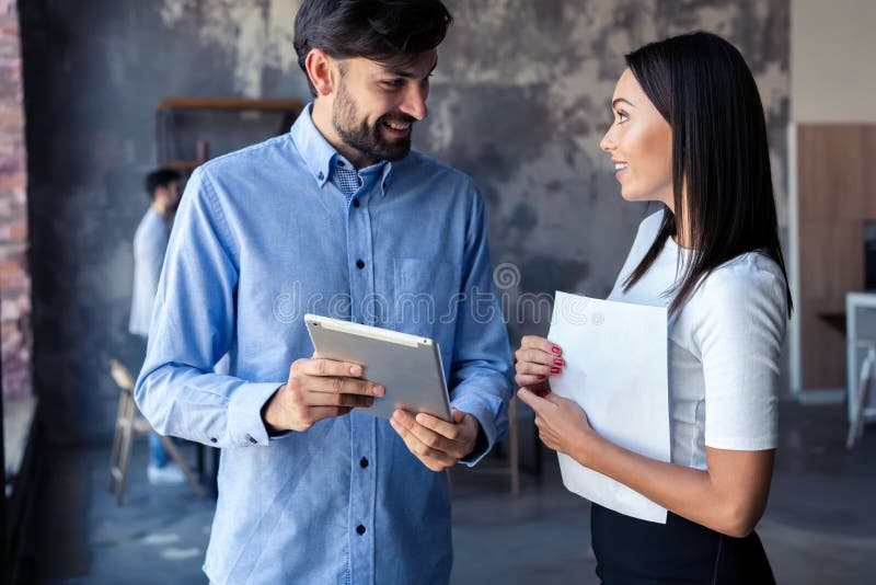 Discussing new business project. Two happy young people in casual wear smiling and looking at digital tablet while royalty free stock photos Discussing new business project. Two happy young people in casual wear smiling and looking at digital tablet while royalty free stock photos