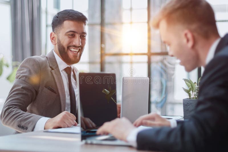 Two happy men working together on a new business project. Discussing the problem. Two confident business man discussing something on the computer