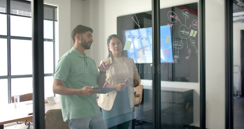 Discussing project, colleagues using tablet and whiteboard in modern office stock video footage