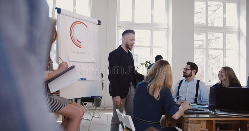 Discussão animada no seminário moderno do escritório, homem de negócios envelhecido médio feliz que fala aos empregados incorpora