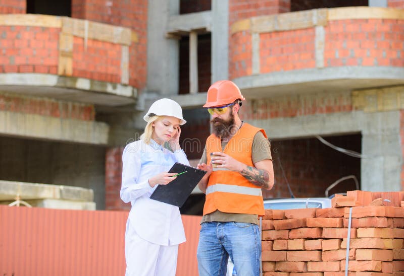 Discuter le plan L'ingénieur et le constructeur de femme communiquent au chantier de construction Concept de communication d'équi photographie stock Discuter le plan L'ingénieur et le constructeur de femme communiquent au chantier de construction Concept de communication d'équi photographie stock