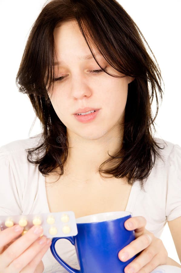 The diseased girl sitting on the bed and look at the pills