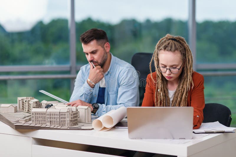 Diseñadores hombres y mujeres creativos cualificados y trabajadores que trabajan con maquetas de edificios y planos en laptop. imagen de archivo