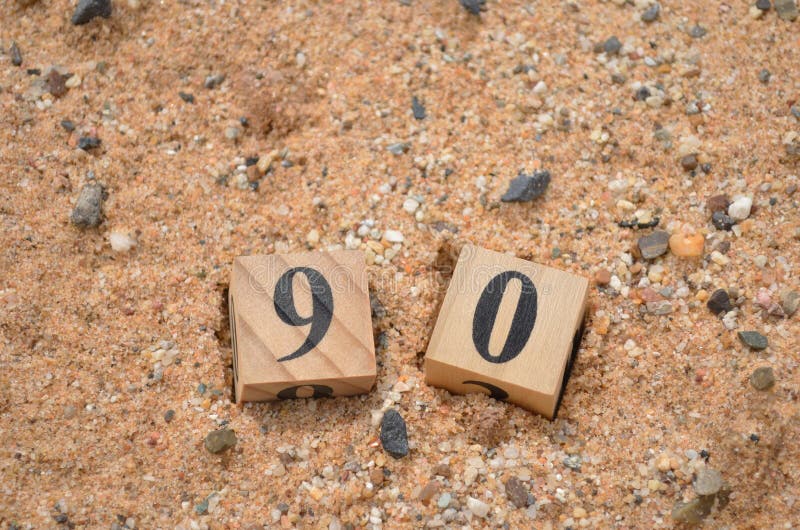 Number 90, rating, award, Cover design in natural concept with a number cube on a sand background. Number 90, rating, award, Cover design in natural concept with a number cube on a sand background.