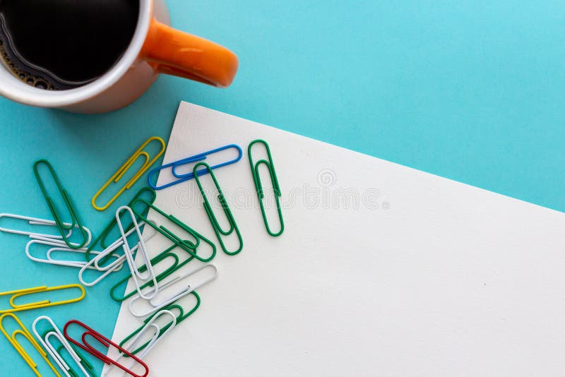 Diseño de escritorio con la taza anaranjada de café y de paperclips coloridos imagen de archivo Diseño de escritorio con la taza anaranjada de café y de paperclips coloridos imagen de archivo