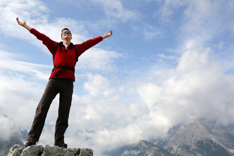 Young mountaineer standing on a rock and enjoying freedom in the mountains. Young mountaineer standing on a rock and enjoying freedom in the mountains