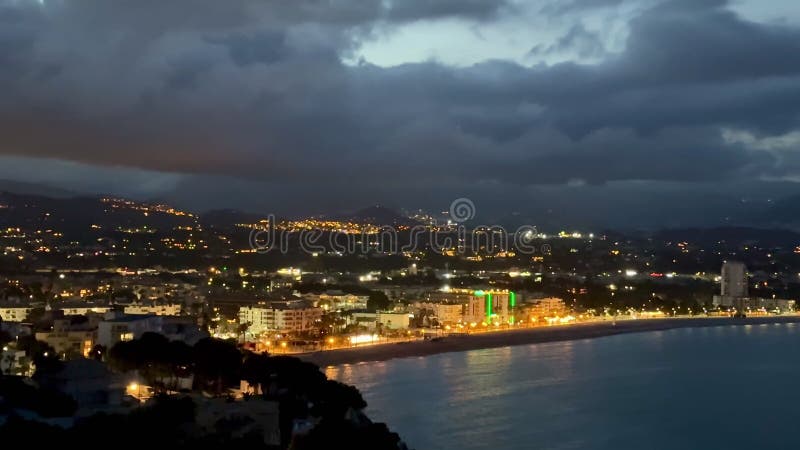 Disfrute de las vistas nocturnas de una ciudad costera con edificios luminosos almacen de metraje de vídeo