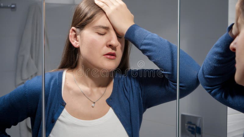 Upset woman suffering from problems in life leaning on mirror in bathroom. Concept of depression, stress, mental illness and problems, loneliness and frustration. Upset woman suffering from problems in life leaning on mirror in bathroom. Concept of depression, stress, mental illness and problems, loneliness and frustration.