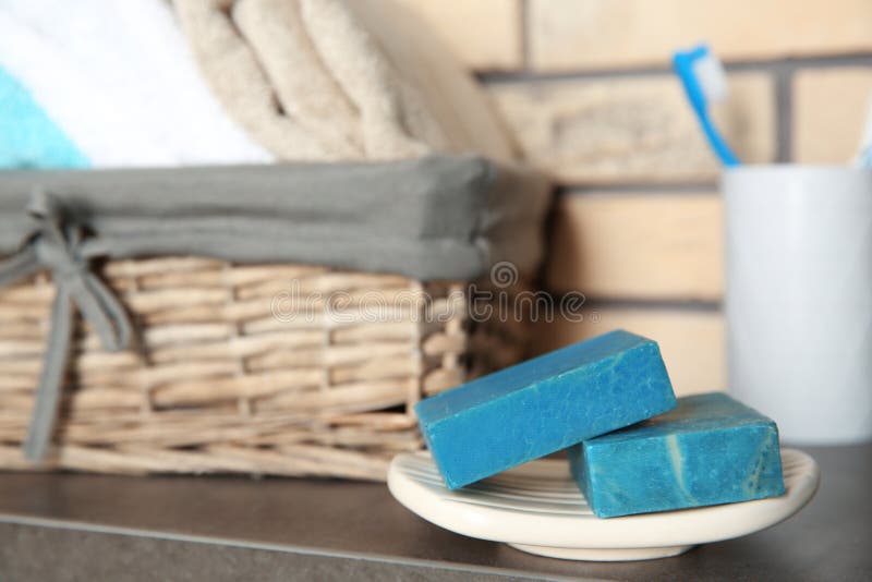 Dish with Blue Handmade Soap Bars on Table in Bathroom. Stock Photo