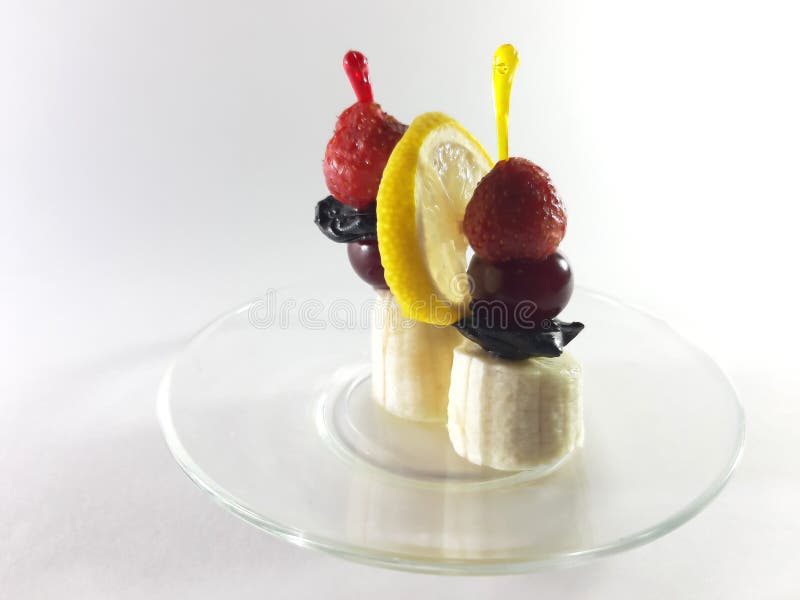 Dish for gourmet. Healthy food. Vegetarian foods on a transparent plate. Berries and fruits. Lemon and cherry for a snack. Photo