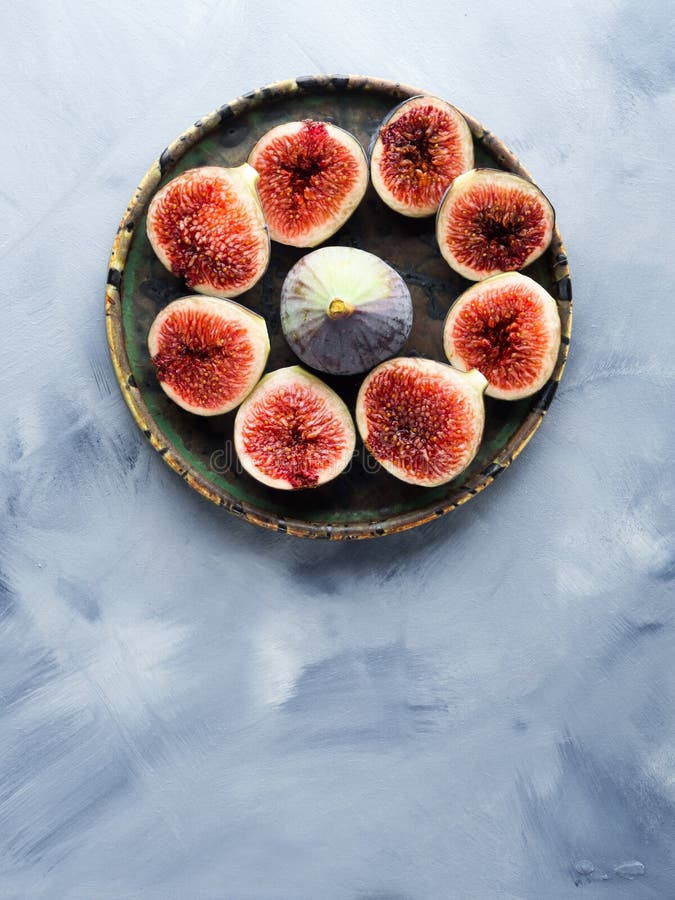 Dish of purple figs on gray background