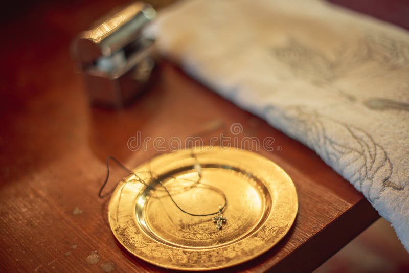 Dish with , pectoral cross for christening on altar. Orthodox baptism of baby. Catholic infant baptism. carpet, prayer-book and a bible in church. baptism accessories. Dish with , pectoral cross for christening on altar. Orthodox baptism of baby. Catholic infant baptism. carpet, prayer-book and a bible in church. baptism accessories