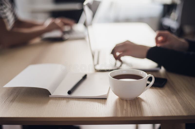 Disparado de um ` s da mulher entrega a datilografia em um teclado do portátil, com um copo do café quente próximo foto de stock Disparado de um ` s da mulher entrega a datilografia em um teclado do portátil, com um copo do café quente próximo foto de stock